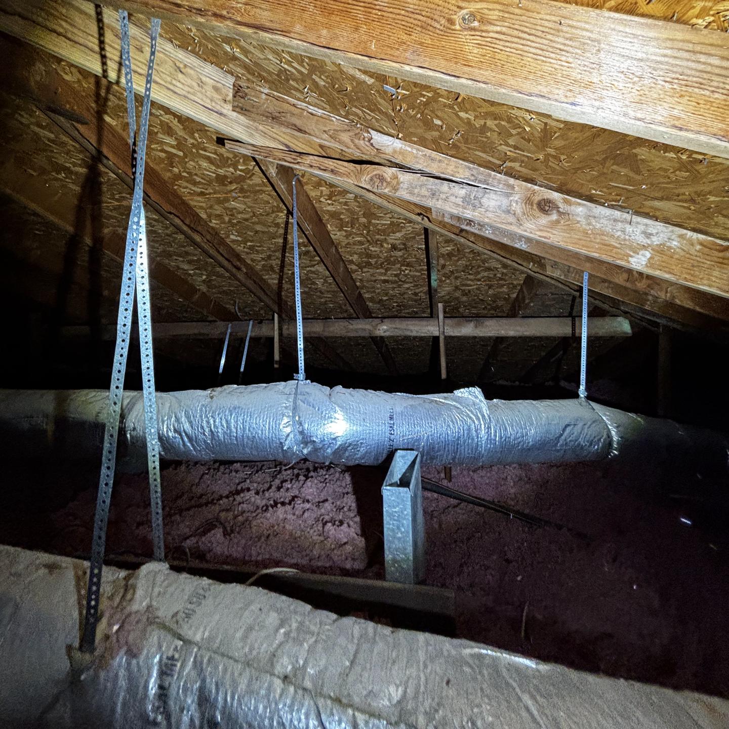 Attic rafters, OSB decking, and an insulated HVAC duct examined during a pre-listing inspection, the kind of area a buyer's inspector will check closely.