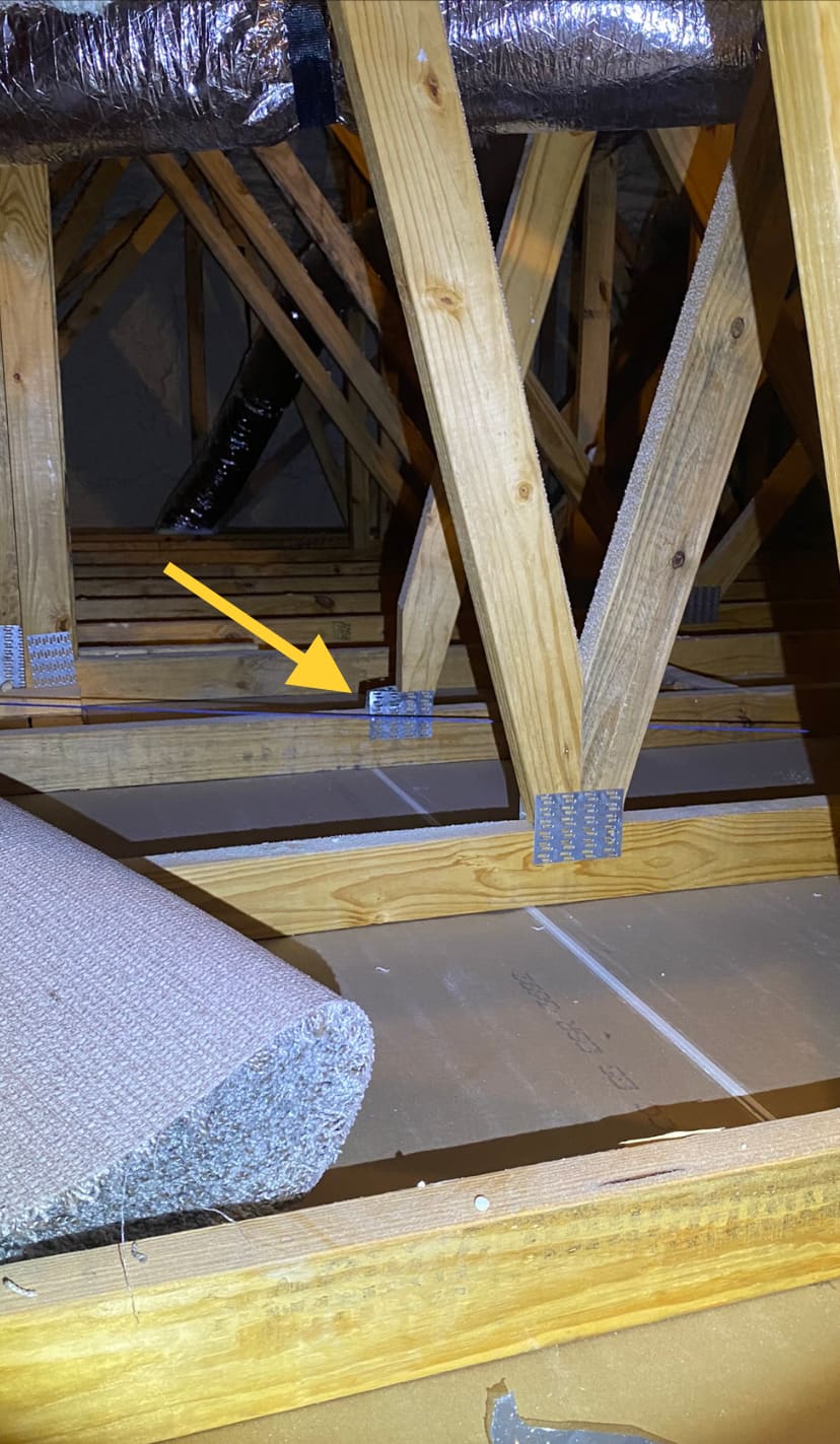 Roof truss framing and insulation inspected in a newly built home's attic.