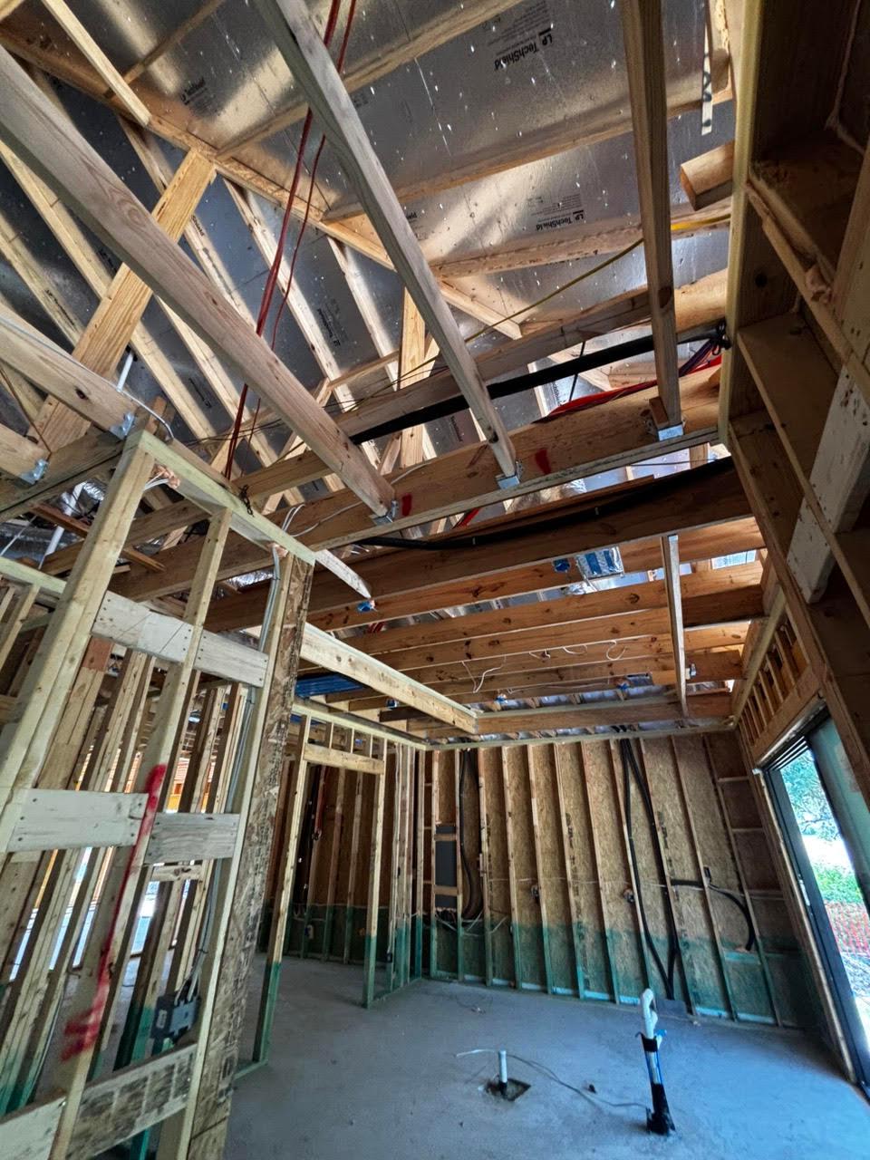 Open wall and ceiling framing with exposed wiring and ductwork in a new construction home during a pre-drywall phase inspection.