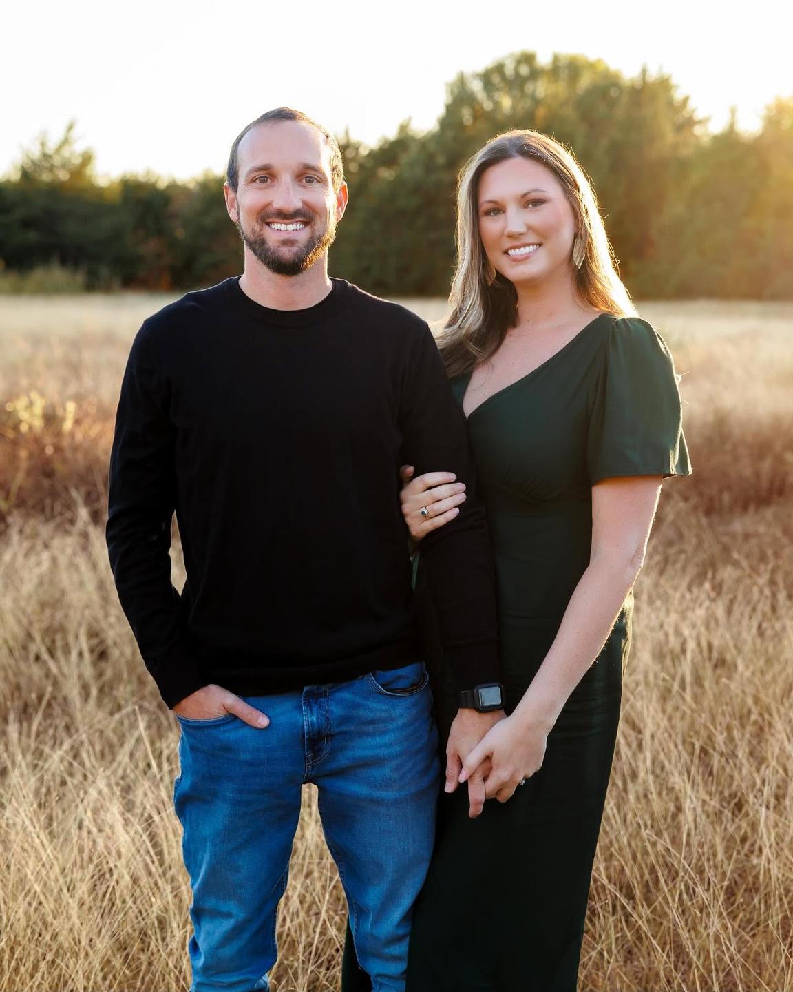 Ricky and Martina Yost of AIM Home Inspections standing arm in arm in a field at sunset.