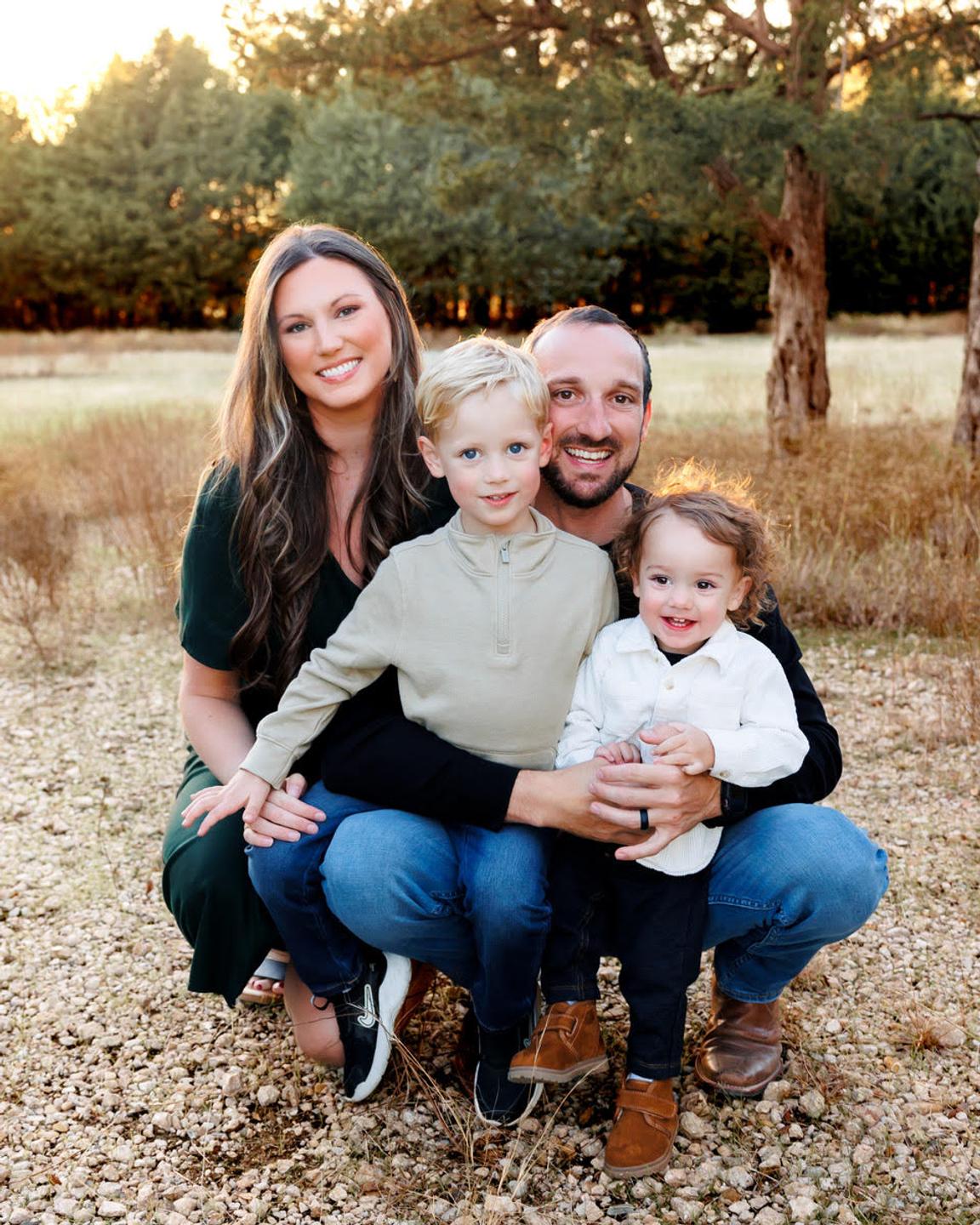 Ricky and Martina Yost of AIM Home Inspections outdoors with their two young sons at golden hour.