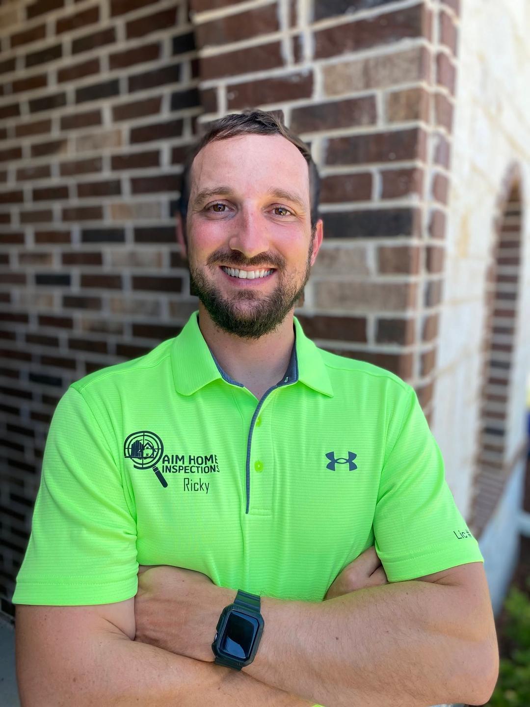 Ricky Yost, owner and inspector at AIM Home Inspections, standing arms crossed in an AIM branded polo shirt.